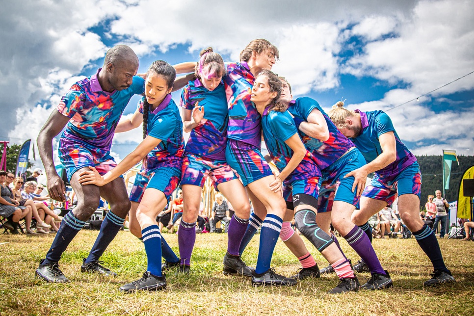 Performers pose as a rugby team in a scrum