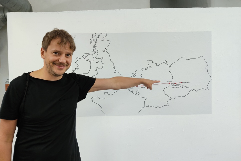 The artist Michal Iwanowski points at Poland on a map of Europe