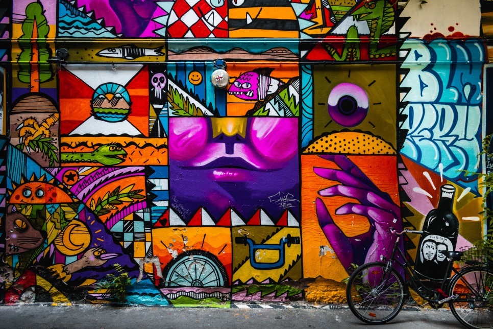 Colourful and bold cartoon-esque graffiti on a wall with a bike leaning against it