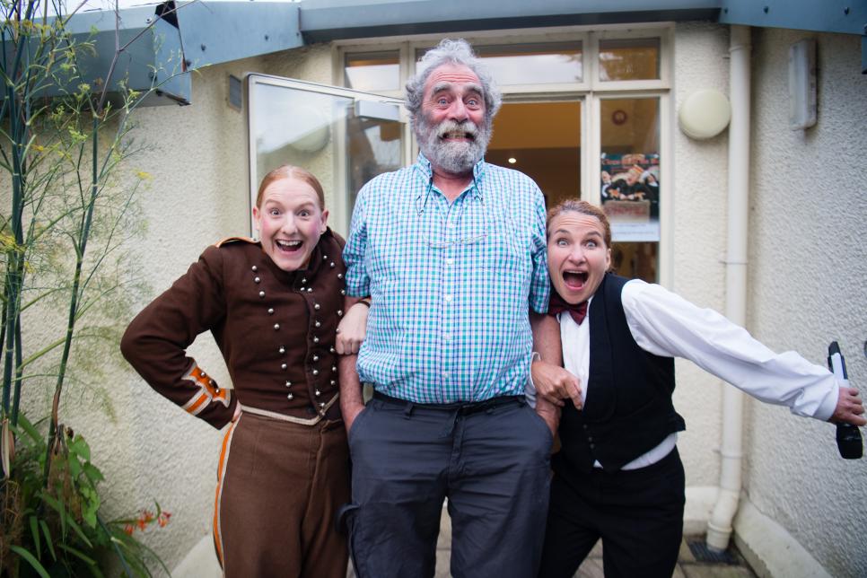 Promoter Des George standing with two performers striking a pose.