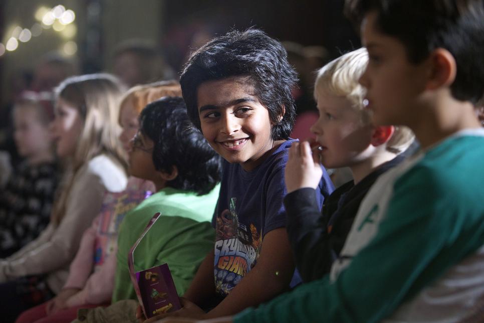 Young children sitting, looking on at an unseen performance.