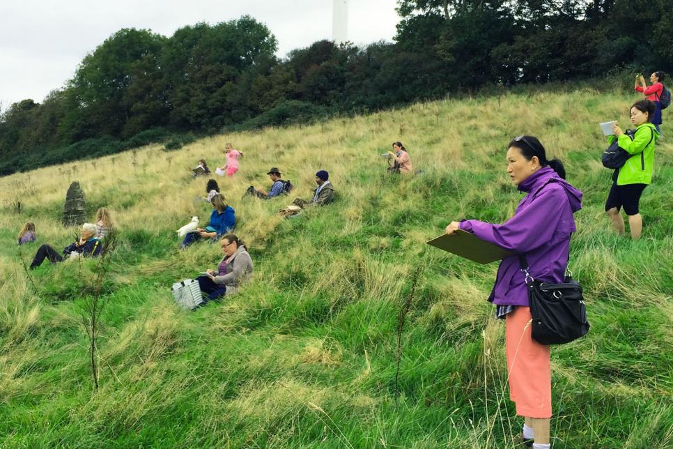 Group of people stand on a hill sketching the view