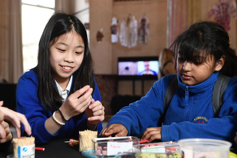 Two kids working at a table with arts and crafts.