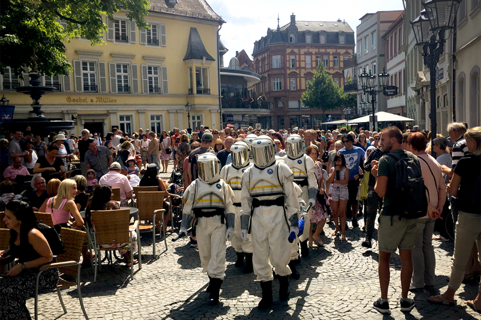 Astronauts walking through crowds in a picturesque German town