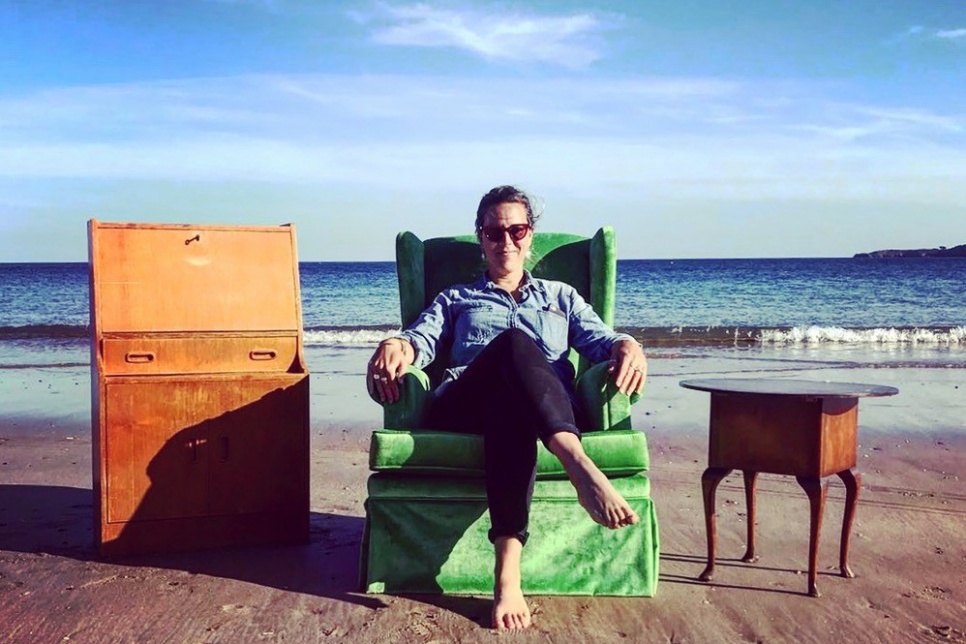 Malú Ansaldo sad on green armchair at the beach on a sunny day