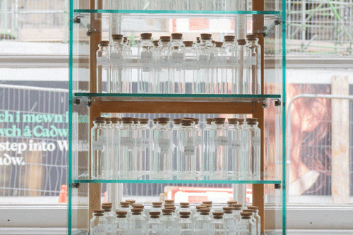 A structure with 4 shelves filled with glass jars of air and cork tops