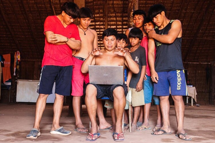 Young Xingu people gather around a laptop