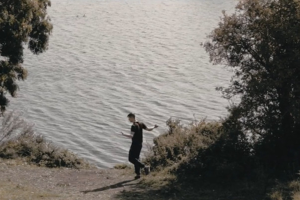 Fearghus O Conchuir dances next to a lake 