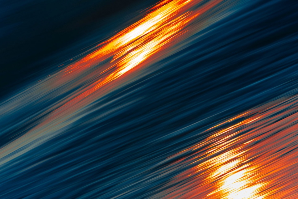 An abstract image of deep blue water with ripples flowing thorugh and 2 spots of light reflecting on the surface