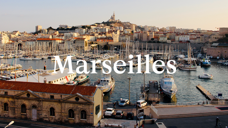 The buildings of Marseilles and boats in the sunshine, with the word MARSEILLES in white as an overlay.