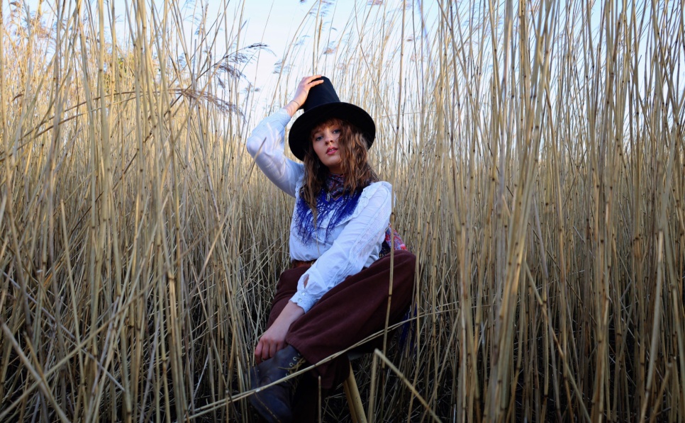 Woman in a Welsh hat (Het Gymreig)  in a field of long grass.
