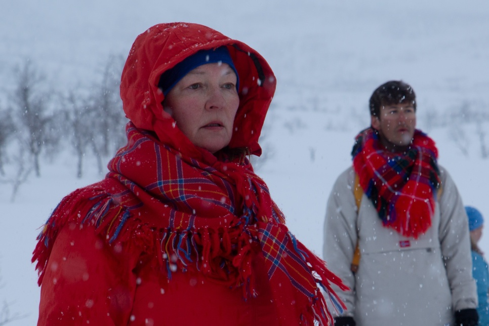 Woman and man in bright red scarfs and winter clothing in a snow scene