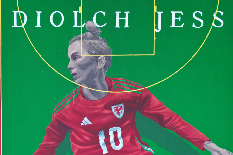 Image of Jess Fishlock in full Welsh kit pained on a pitch